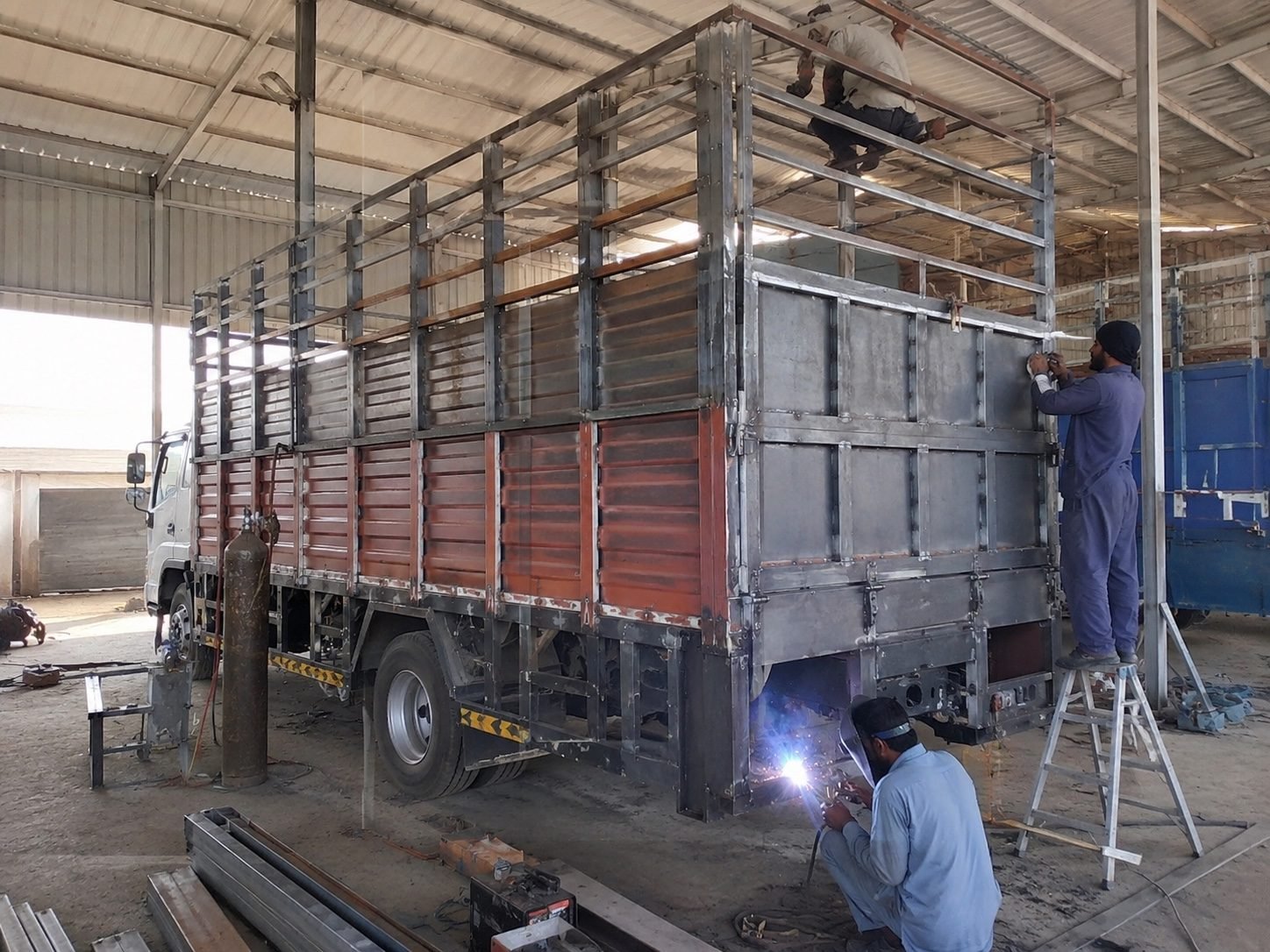 Welders building a custom truck body at MRFT workshop, Misfah, Oman